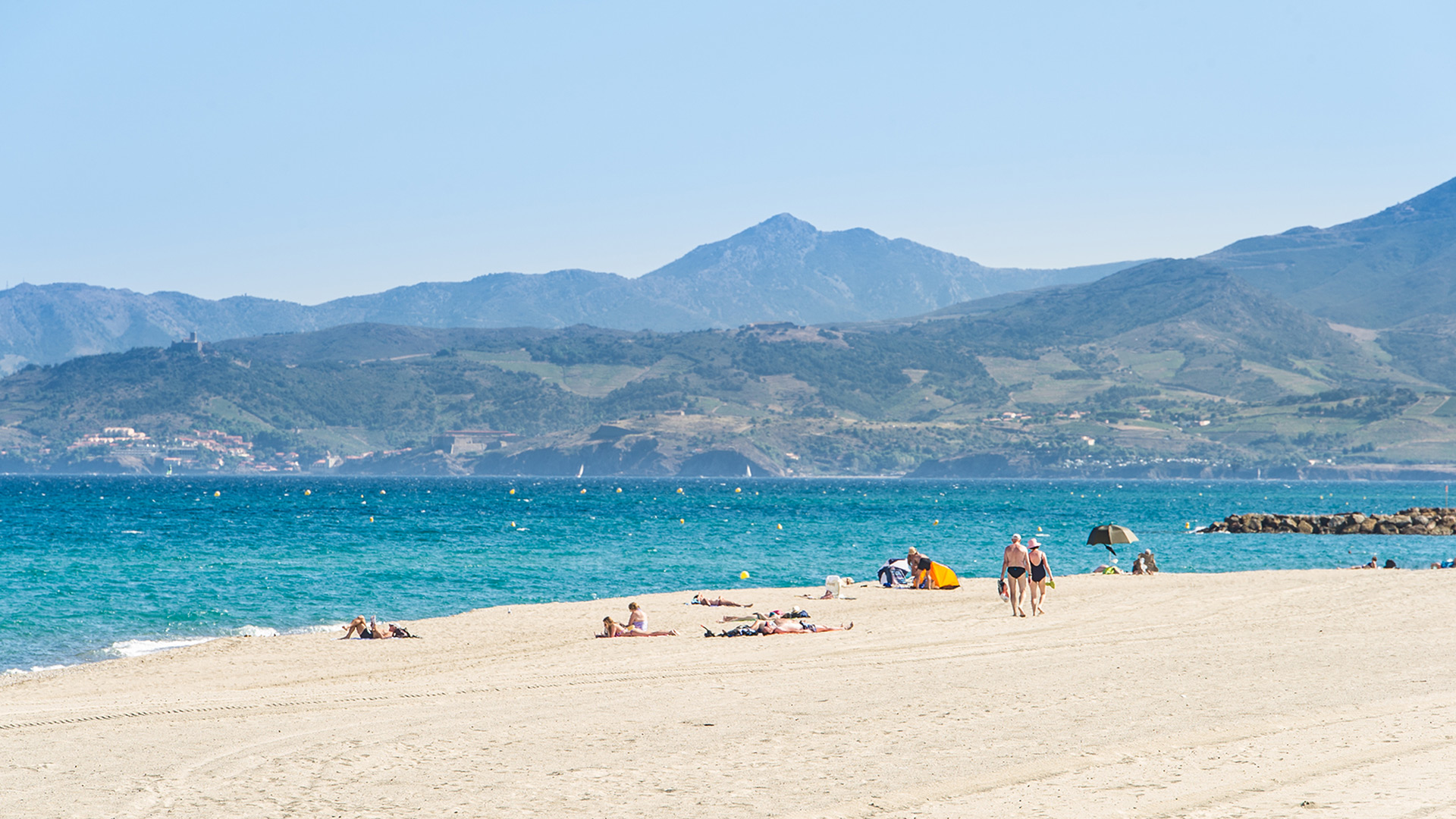 La plage sud de Saint-Cyprien avec son sable fin, la mer Méditerranée et les montagnes des Pyrénées en arrière-plan.