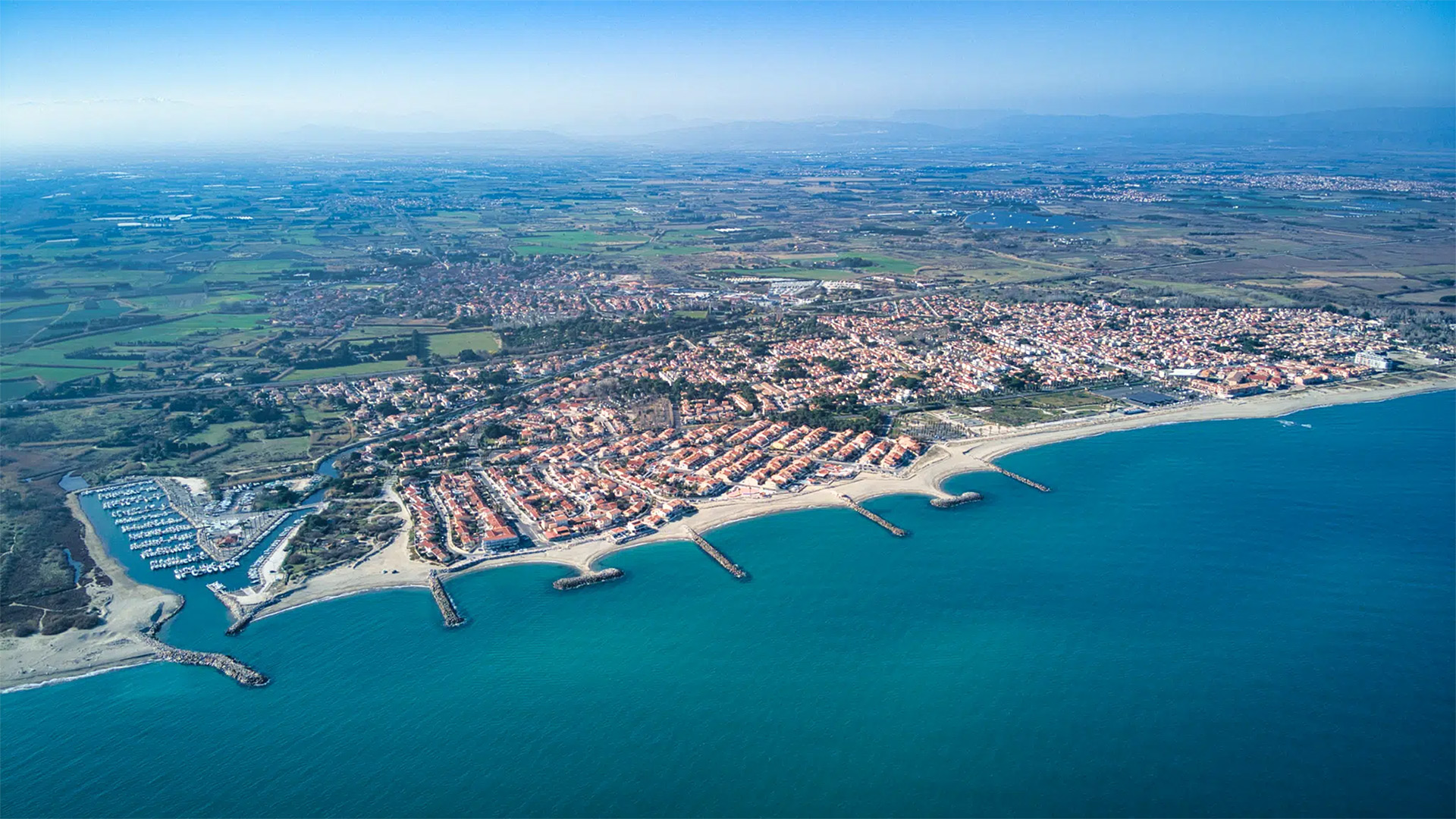 Vue aérienne de Sainte-Marie-la-Mer montrant la plage, le port et le littoral des Pyrénées-Orientales.