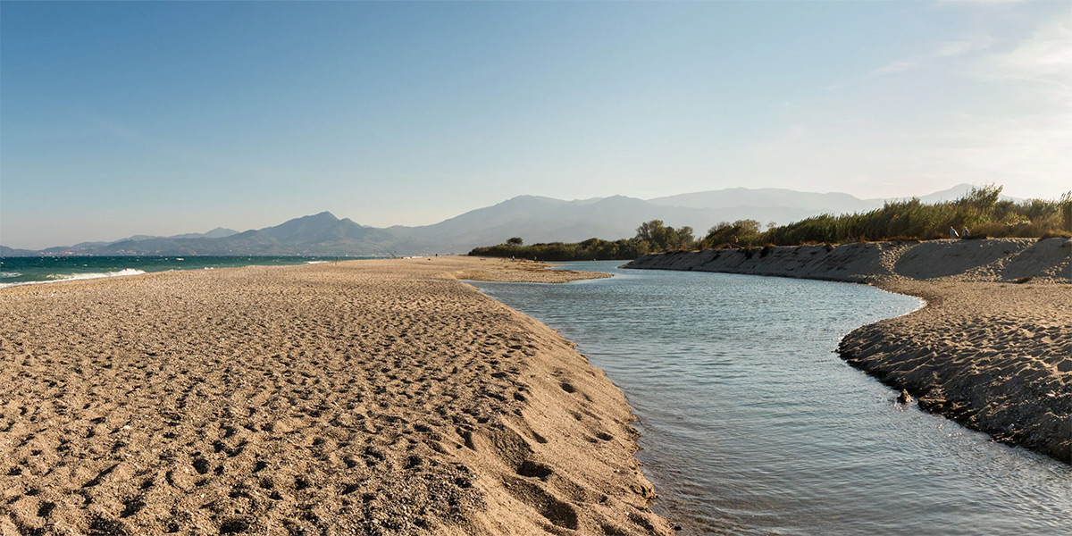 Vue panoramique de la plage de Torreilles avec l'embouchure du Bourdigou, les dunes, la Méditerranée et le massif du Canigou en arrière-plan